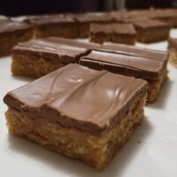 Scotcheroos, featuring crispy rice cereal mixed with a chewy peanut butter base, topped with a smooth chocolate -butterscotch layer. These handmade, no-bake treats are perfect for sweet lovers, gifting, and indulging in a nostalgic dessert experience