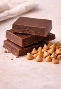 Premium chocolate squares stacked beside butterscotch chips, key ingredients used to create the rich chocolate topping on weScotchoo Scotcheroo Bars.