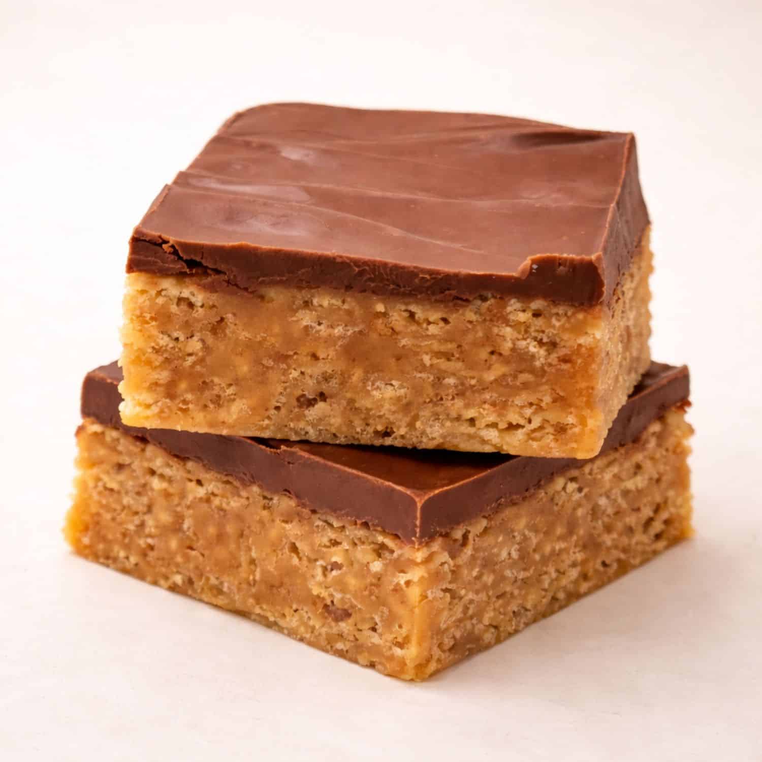 Close-up of handcrafted peanut butter chocolate rice krispie bars showing the chewy rice cereal base and smooth chocolate butterscotch topping.