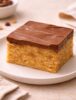 Thick Scotcheroo bar with chocolate and butterscotch topping on ceramic plate in warm boutique kitchen setting {{brizy_dc_image_alt imageSrc=