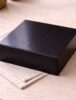 Glossy black Scotcheroo gift box closed and ready for shipping, displayed on a neutral linen surface with soft natural lighting. {{brizy_dc_image_alt imageSrc=